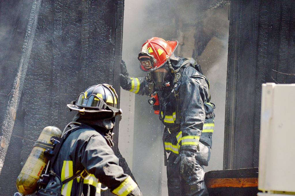 Lt. James Meek, of Central Whidbey Island Fire and Rescue, stands in the doorway of a house on Classic Road destroyed by a fire Wednesday. Photo by Laura Guido/Whidbey News Group