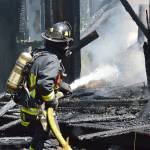 Firefighter Jeffrey Rhodes sprays inside a house on Classic Road that caught fire Wednesday. The building was already falling apart by the time fire crews arrived. Photo by Laura Guido/Whidbey News Group