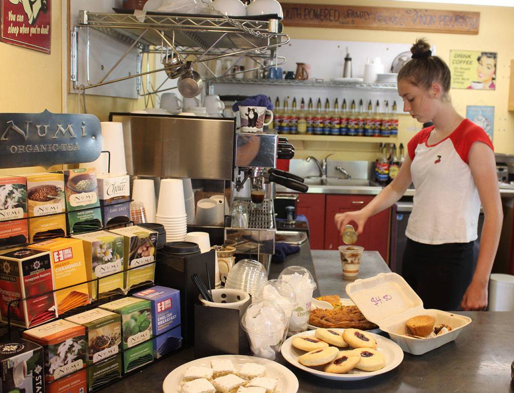 Emelia Stahl prepares an iced latte at South Whidbey Commons Cafe and Books, a popular gathering spot in Langley. Run by a nonprofit organization, the cafe teaches barista and culinary skills to youth. The staff will be preparing and selling food at Saturdays debut Bluesberry Festival, which may become an annual Commons fundraiser.
