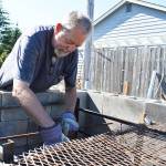 John Ryan demonstrates how the pig butt meat will be skewered to be able to fit more in the large cinder block pit he made for Oak Harbor Pigfest. He and other festival organizers will smoke 4,000 pounds of pork in a pit that will include three additions to the one pictured. Photo by Laura Guido/Whidbey News-Times