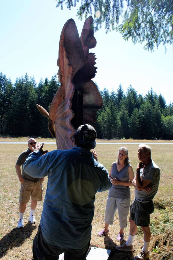 Artist Alexei Kazantsev has visitors examine the back of his Amelia Earhart sculpture to explain the method of sand casting. (Photo by Patricia Guthrie/Whidbey News Group)
