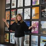 Stacie Burgua, outgoing executive director of Whidbey Island Center for the Arts, stands in front of posters from the more than 75 theater productions staged during her 18-year tenure. (Photo by Patricia Guthrie/Whidbey News Group)