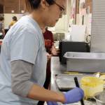 To prevent the pie crust from burning, Tran Hong quickly applies egg wash on the crust before applying aluminum foil strips around the pie.