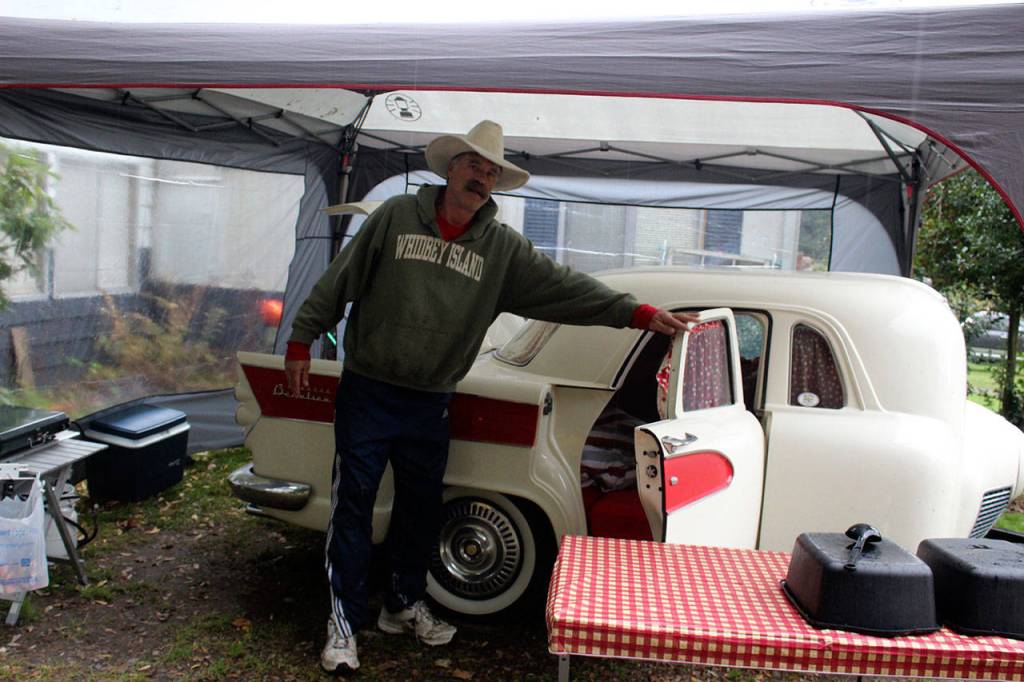 John Norris stands beside Miss Piggy, a camping trailer built from many spare parts of cars, trucks and motorcycles. It was assembled by Brian Woods of British Columbia.
