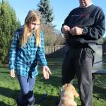 With her grandfather, Kirk Lacewell, Piper Pontius plays with Scout who she says is bound for canine stardom since making a mammoth discovery in the backyard. (Photo by Patricia Guthrie/Whidbey News Group)