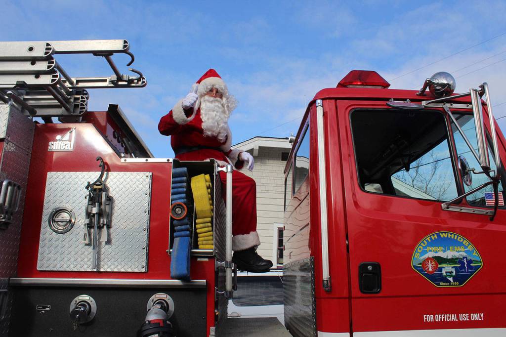 The real Santa Claus rides atop a South Whidbey Fire District fire engine, the traditional red-on-red ending to the Holly Jolly Parade.