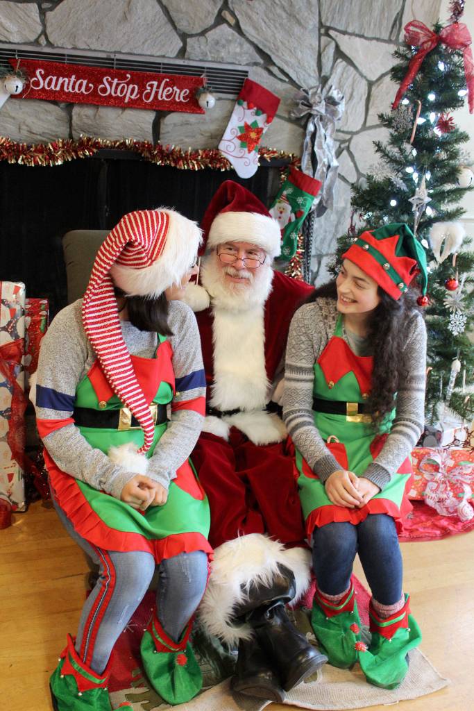 Elves Natalie Monetti, left, and Tess Patty-Caldwell visit Santa for a fun photo opportunity Sunday at the Clinton Winter Market. (Photo by Patricia Guthrie/Whidbey News Group)