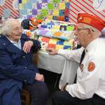 Frank Thorton, of Marine Corps League Detachment 1451, speaks with Ginny Mayer, who stitched together four dozen kid-size quilts. They are being given away to families in need through Toys for Tots and Holiday House at South Whidbey Community Center. (Photo by Patricia Guthrie/Whidbey News Group)
