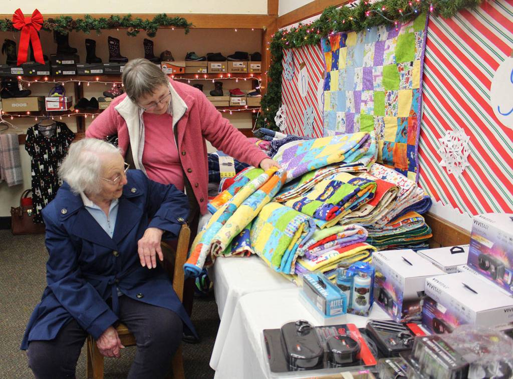 Anita Smith looks at the stacks of childrens quilts made by 90-year-old Ginny Mayer.