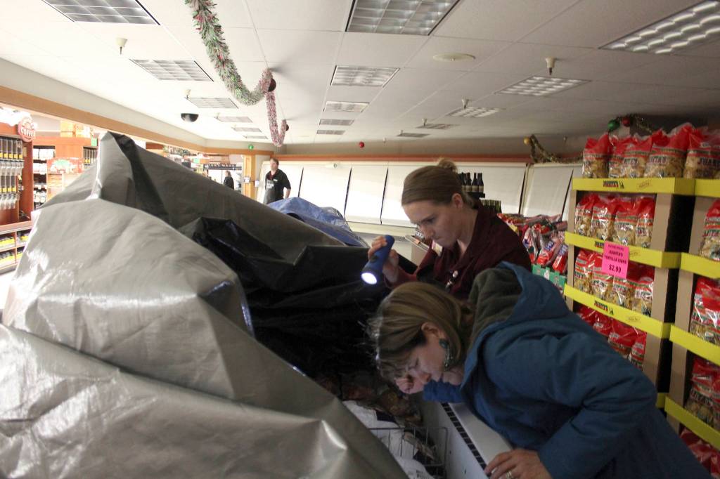 Nicolle Wilson helps a customer find meat at Payless grocery store in Freeland. Refrigerated foods were kept under tarps to keep the cold in when power went out around 11 a.m. Thursday.