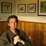 Craig Johnson poses beneath a wall of his artwork in the couples home. (Photo by Patricia Guthrie/Whidbey News Group)