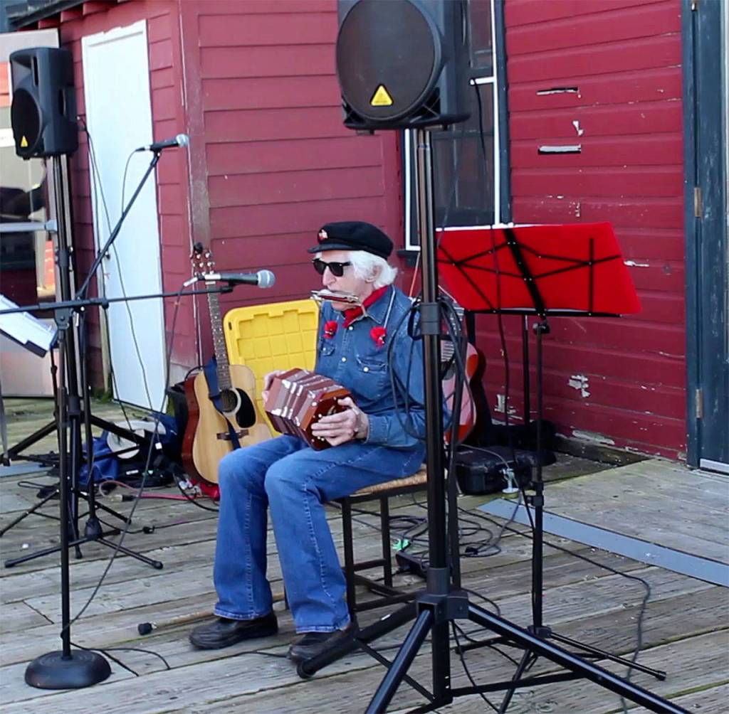 Peter Lawlor plays sea shanties on his concertina and harmonica on the Coupeville wharf during a birthday party for the historic schooner, Suva. (Photo by Patricia Guthrie/Whidbey News Group)