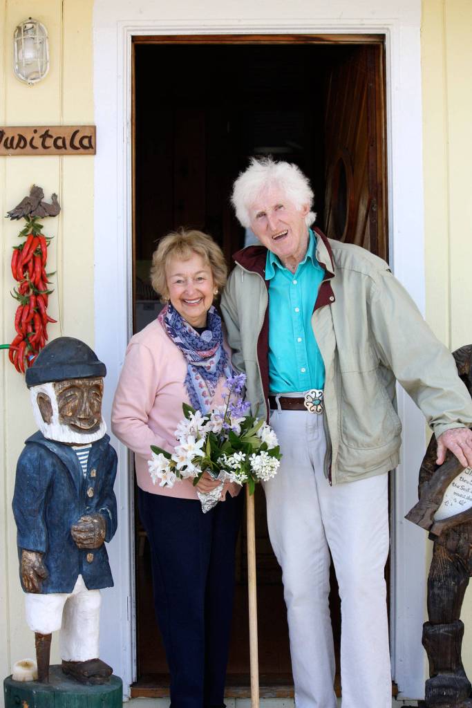 Roberta Brown and Peter Lawlor pose in front of Peters sea cottage in Clinton. The carved wood sign, Tusitala, means teller of tales in Samoan. (Photo provided)