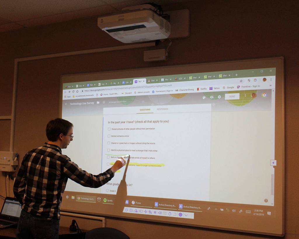 Ian Turner, director of operational technology at South Whidbey High School, demonstrates ceiling projectors that use information from laptops and show it on white boards.