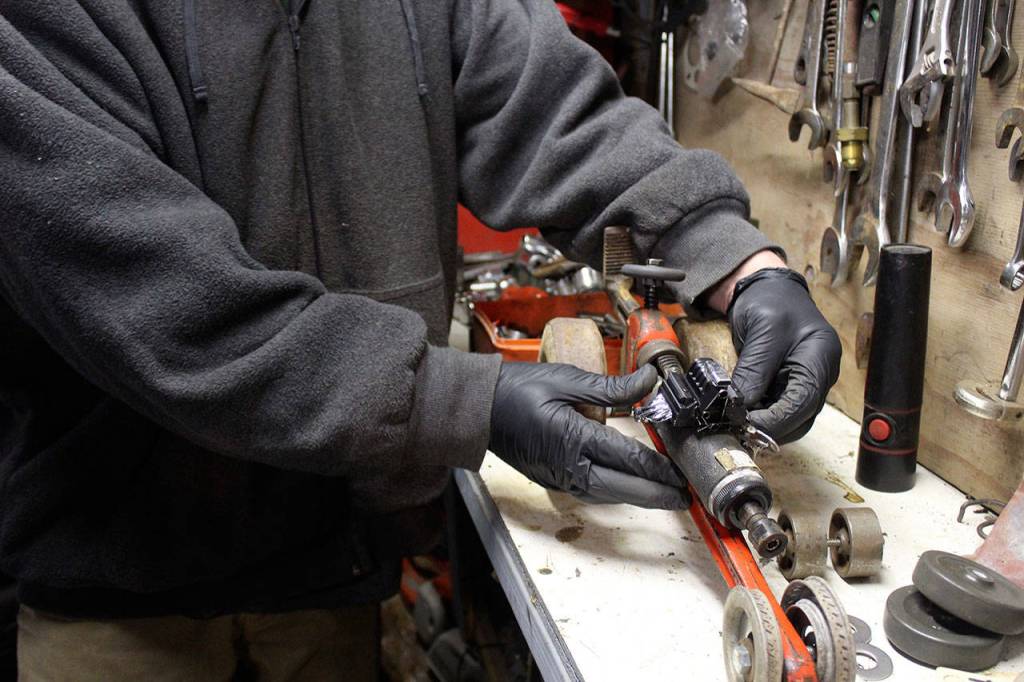 Turning another pipe wrench into a drag car and recycled art work, John Norris tries on some possible parts. (Photo by Patricia Guthrie/Whidbey News Group)