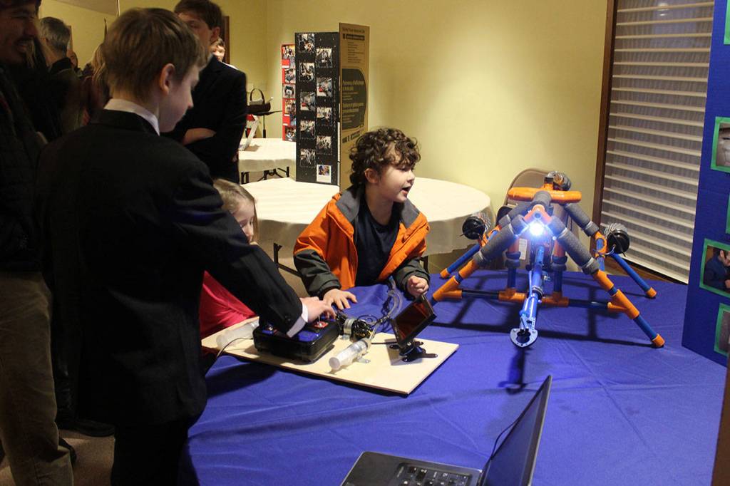 Slater Canright, left, helps Morphew Momo Jenkins operate the underwater robot he built that is equipped with a video camera.