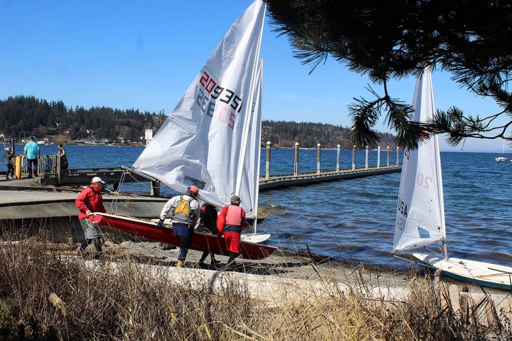 Members of the South Whidbey Yacht Club carry their Laser class sailboats to waters edge at Holmes Harbor. Sunny skies and breezy conditions Sunday made for an ideal early sail into spring on the streamlined sleek boats. Club races usually start in May.