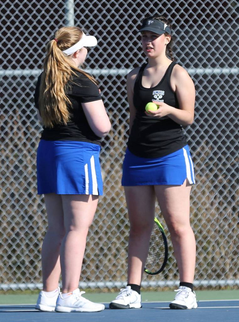 Annika LeWarne, left, and Elizabeth Simmons discus strategy during a break in third doubles.(Photo by John Fisken)