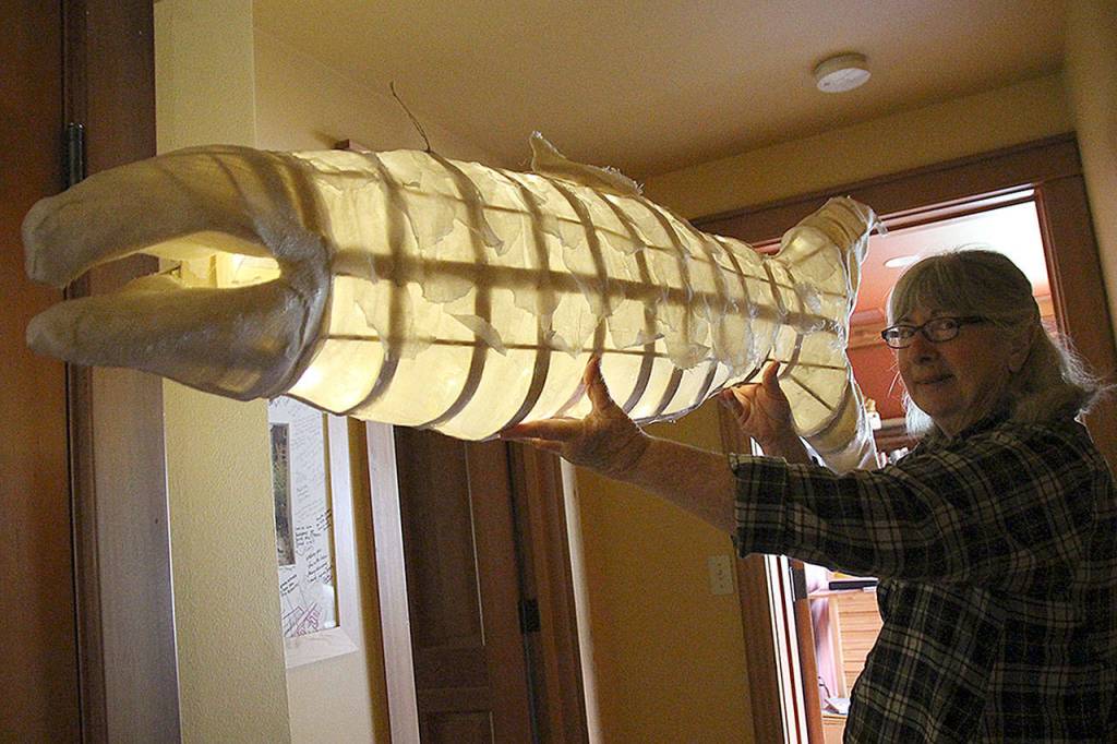 Molly Brown holds her glowing salmon, demonstrating the shine of the small inner lights strung through the hollow fish. The parade may not show the lights, as it takes place during the day. However, the artists plan to bring the salmon to Olympia in support of various whale-friendly legislation. (Photo by Maria Matson/Whidbey News Group)