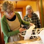 Artist Melissa Koch (front) wraps gauze around the reed skeleton of the five-foot salmon she and Molly Brown are crafting. Their salmon will be featured in the upcoming Welcome the Whales Parade when the city of Langley celebrates the return of traveling gray whales. (Photo by Maria Matson/Whidbey News Group)