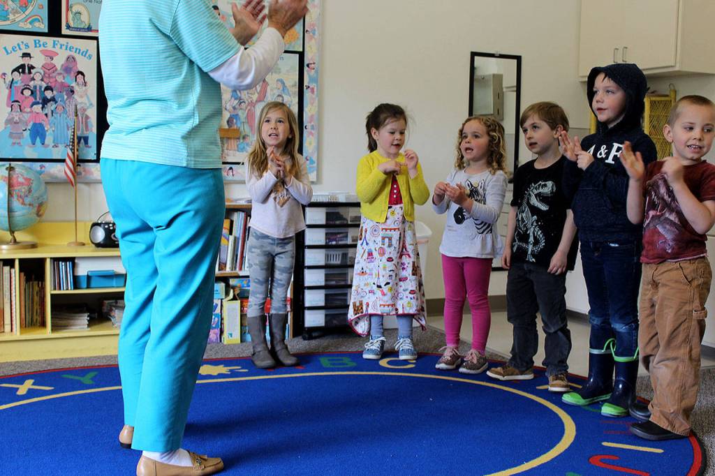 Johnson leads a session of head, shoulders, knees and toes, knees and toes for one of three groups of children rotating through her preschool classroom.