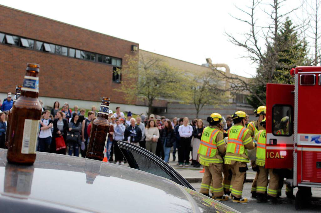 Many South Whidbey rescue agencies participated in the mock emergency response scene designed to remind teens that driving while impaired or distracted can be deadly. Law enforcement officers placed scattered empty beer bottles and a drained liquor bottle atop the roof of the mangled car while investigating.