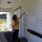 Bayview Community Hall board president Carie Elder checks spots where paint has flaked off over many years. Lead paint needs to be removed from the exterior of the nearly 100-year-old building before its repaired and painted. Photos by Patricia Guthrie/Whidbey News Group