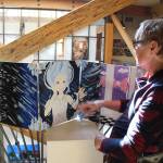 Peggy Gilmer looks over a ten-panel piece called Unhinged Reflections by student artist Casey Rogers at the Art with a Message exhibit. On view until June 9 at Bayview Cash Store, the annual all-island high school art show is sponsored by Goosefoot. (Photo by Patricia Guthrie/Whidbey News Group)