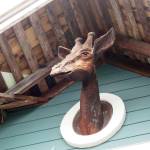 A wooden giraffe carving hangs at the top of the blue Giraffe Building in Langley.