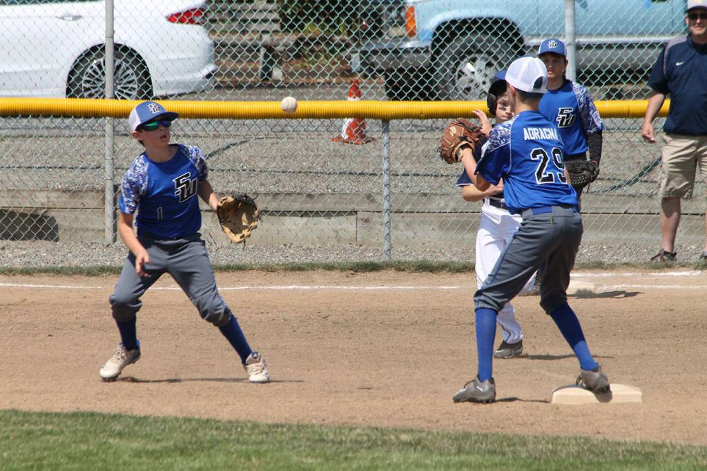 Second baseman Alexander Zarifis flips to shortstop Jaden Adragna Saturday.(Photo by Jim Waller/South Whidbey Record)