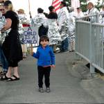 Demonstrators in Coupeville Friday evening hold up signs protesting immigration policies as part of a national Lights for Liberty event.Everson Welch, 3, attended with his family. (Photo by Maria Matson/Whidbey News-Times)