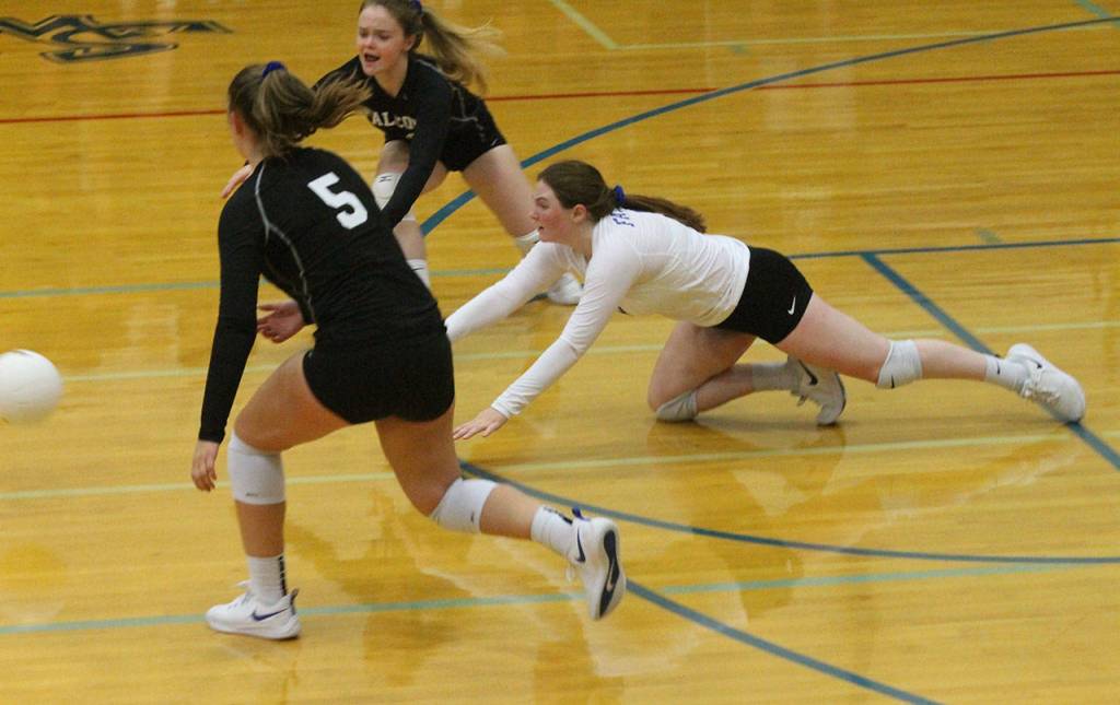 Kayla Knauer dives between Kamryn Wilson (5) and Joanie Welever in an attempt to dig a Sultan hit.(Photo by Jim Waller/South Whidbey Record)