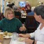 Volunteer Bobbie Olzta, left, and Island Senior Resources board member Julie Joselyn share a meal at the opening of Leos Place, a new intergenerational dining hall in Bayview. Photo by Wendy Leigh / South Whidbey Record