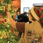 Photo by Kira Erickson/Whidbey News Group                                Girl Scout Kalea Staats places an ornament on the Giving Tree in the Bayview Cash Store on Dec. 5.