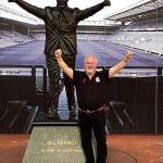 Crispin Roberts stands next to the statue of Bill Shankly outside Liverpools soccer stadium. (Provided photo)