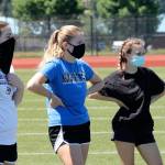 Oak Harbors Emma Erskine, left, Bailey Trease and Emily Miller listen to instructions before a drill at offseason workouts Monday. Health guidelines require athletes to wear masks when within six feet of each other. (Photo by Jim Waller/Whidbey News-Times)