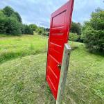 The house on the 17-acre property sits too far to see behind the red door along Cultus Bay Road in Clinton on Whidbey Island. (Andrea Brown / The Herald)
