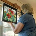 Photo by Kira Erickson/Whidbey News-Times                                Artist Christine Crowell hangs a mosaic piece of hers in the window of Artworks Gallery.