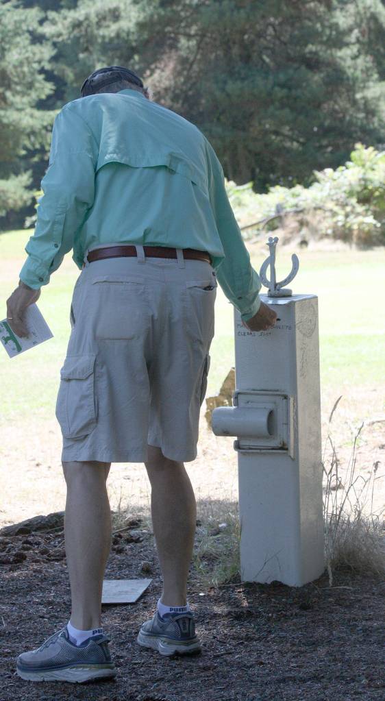 Players at the Island Greens golf course pay by the honor system. Here a customer places his payment in a drop box Monday. (Photo by Jim Waller/Whidbey News-Times)