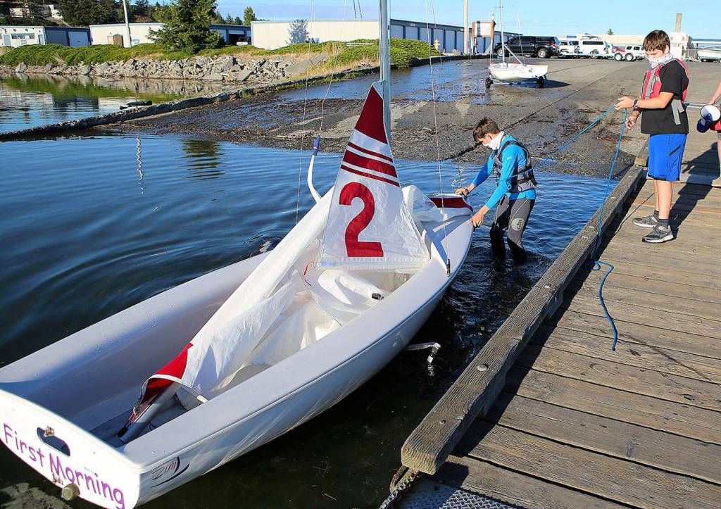 Joshua Odeneal and Gideon Odeneal bring their boat ashore after practice. (Photo by John Fisken)
