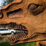 A Tyrannosaurus rex appears to eat a car at a home owned by Burt Mason and Mary Saltwick in Freeland on Whidbey Island. (Andy Bronson / The Herald)