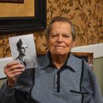 Frank Burns, now in his 90s, holds a photo of himself when he was still in training with the U.S. Army. Burns fought in the Second World War and was interviewed by Rishi Sharma recently about his experience. Photo by Emily Gilbert/Whidbey News-Times