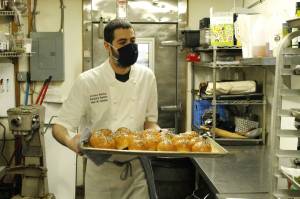 Head Chef Zachary Harris transports a pan of freshly baked buns in Prima Bistros kitchen. The Langley restaurant, like many other businesses on Whidbey, is looking for more staff as the spring season ramps up. Photo by Kira Erickson/Whidbey News Group
