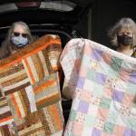 Patricia Griffin, left, and Darcy Sinclair hold up blankets recently made by the group.