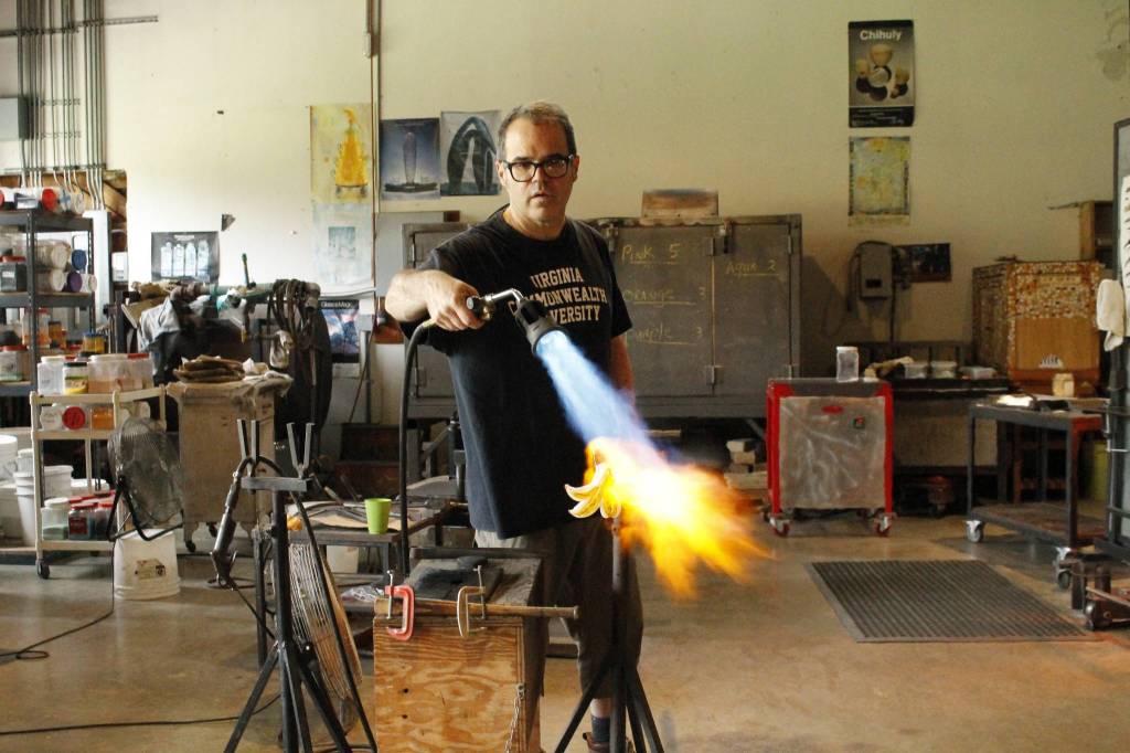 Singleton uses the flame of a gas torch to heat up a glass-blown lily. (Photo by Kira Erickson/South Whidbey Record)
