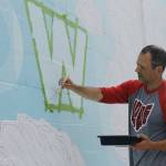 Artist Jeremy Jarvis paints words on his new mural in Langley. (Photo by Kira Erickson/Whidbey News-Times)