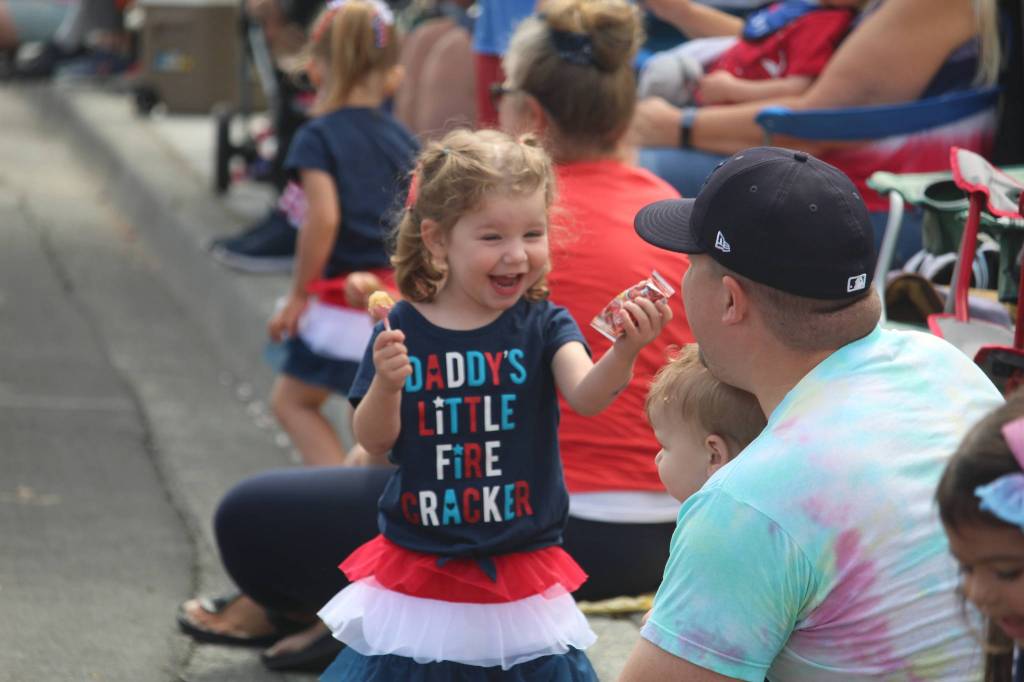 Espyn Gassett, 3, shows her father the candy she got at the parade. (Photo by Karina Andrew/Whidbey News-Times)