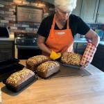 Photo provided
Sue Mills, the volunteer coordinator of the South Whidbey hub for Community Loaves, with four finished loaves of honey oat, whole grain bread.
