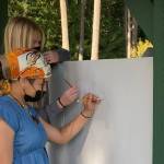 Junior Simone White, front, and senior Mikenna Wicher sketch on the side of the new farmstand. (Photo provided)