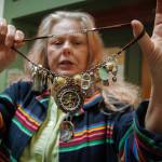 Photo by David Welton
Mixed media artist Sarah Dial Primrose shows off a necklace made of rocks, shells, pop tabs and a crushed Starbucks cap that she has dubbed Beach Party. Her art is on display as part of the Rags, Rubbish, and Refuse exhibit at the Bayview Cash Store.